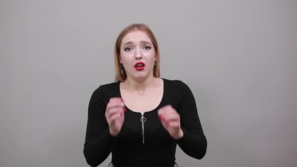 Joven chica rubia en chaqueta negra mujer aterrorizada sostiene sus manos a la cara
 - Metraje, vídeo