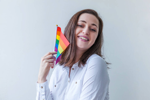 Bella ragazza lesbica caucasica con bandiera arcobaleno LGBT isolato su sfondo bianco cercando felice ed eccitato. Giovane donna Gay Pride ritratto. Parità di diritti per il concetto di comunità lgbtq - Foto, immagini