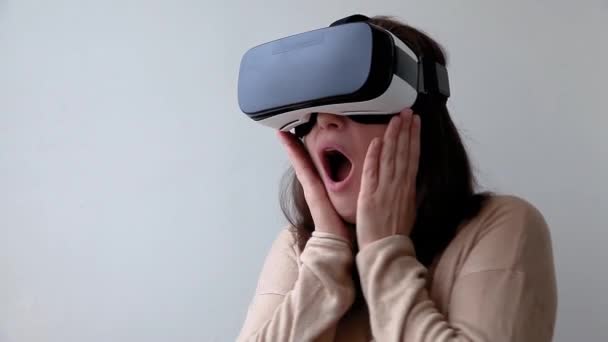 Souriez jeune femme portant en réalité virtuelle casque de lunettes VR casque sur fond blanc. Smartphone utilisant des lunettes de réalité virtuelle. Technologie, simulation, hi-tech, concept de jeu vidéo - Séquence, vidéo