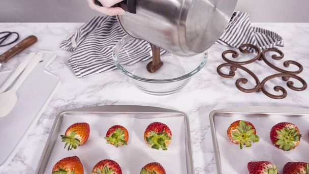Schritt für Schritt. Bio-Erdbeeren in eine Schüssel mit geschmolzener Schokolade tauchen, um schokoladenüberzogene Erdbeeren zuzubereiten. - Foto, Bild