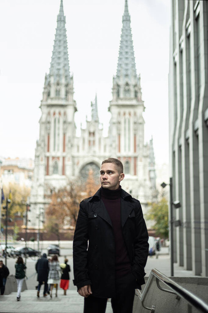 Tyylikäs mies musta trench takki ja poolo kaula goottilainen katedraali tausta
 - Valokuva, kuva