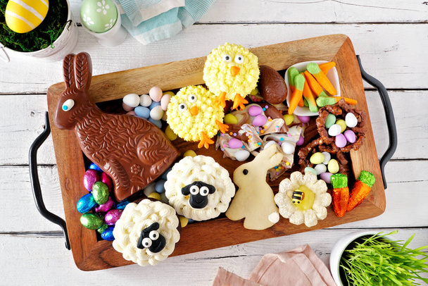 Húsvéti édességtálca, desszertek és édességek választékával. Top kilátás nyílik a fehér fa háttér. Tavaszi nyaralás élelmiszer koncepció. - Fotó, kép