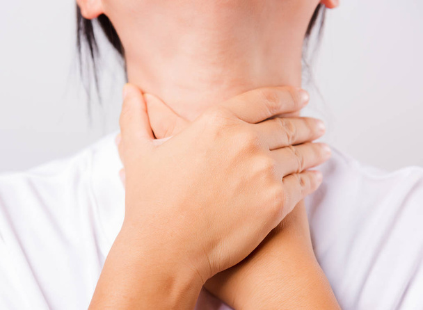 Asian beautiful woman Sore Throat or thyroid gland problem her useing Hand Touching Ill Neck on white background with copy space, Medical and Healthcare concept - Photo, image