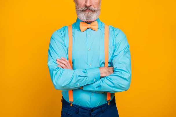Cropped photo of handsome cool clothes grandpa hands crossed not smiling perfect groomed mustache beard wear blue shirt suspenders bow tie pants isolated yellow color background - Fotografie, Obrázek