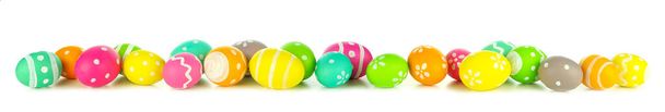 Húsvéti tojások szétszóródva alkotnak egy hosszú határ elszigetelt fehér alapon. Élénk színek. - Fotó, kép