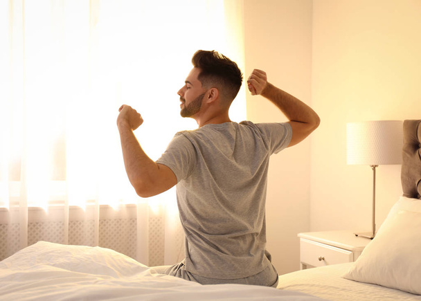 Young man stretching on bed at home. Lazy morning - Photo, image
