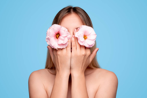 Anonymous woman hiding face behind hands and flowers - Фото, зображення