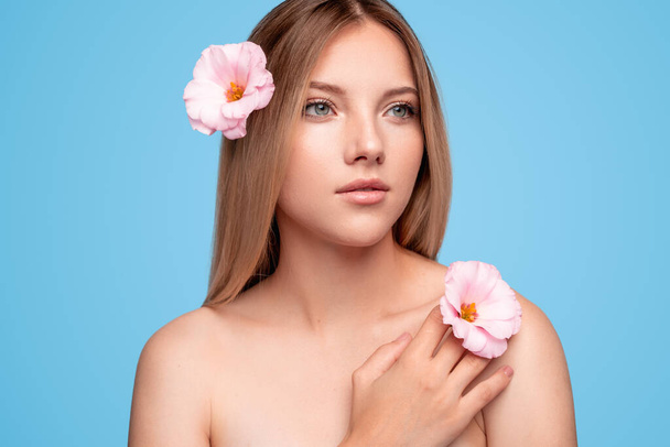 Beautiful lady with flowers touching skin - 写真・画像