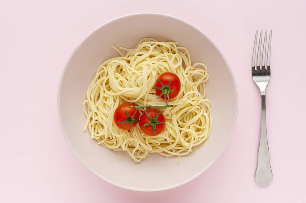 Zelfgemaakte spaghetti met tomatensaus en basilicumsaus, van bovenaf gezien op roze achtergrond. Italiaanse pasta.Flat lag. - Foto, afbeelding