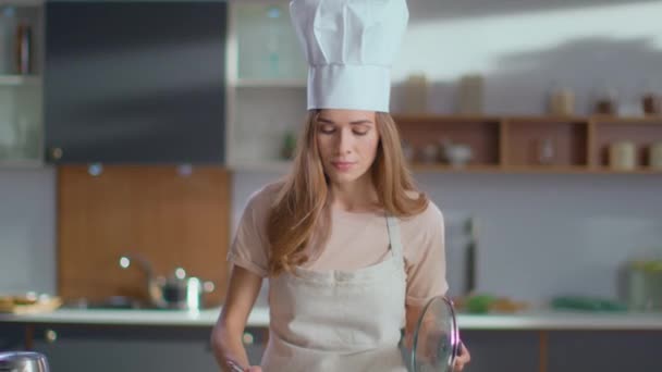 Chef tasting soup on kitchen. Woman in uniform cooking soup on stove - Felvétel, videó