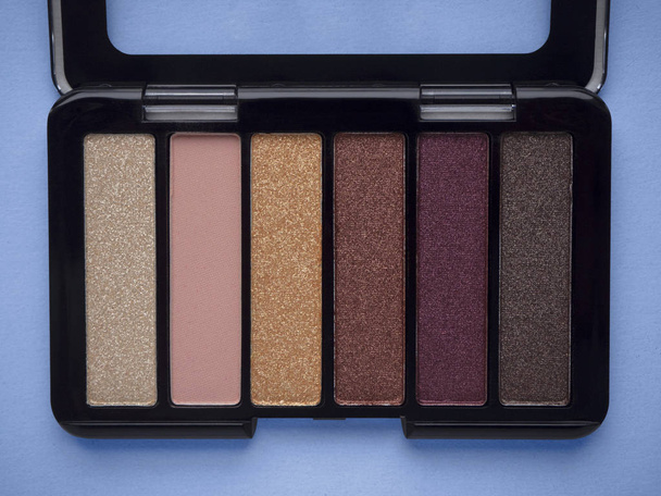 Nude eyeshadow palette in black case top view isolated on blue background.  - Photo, Image