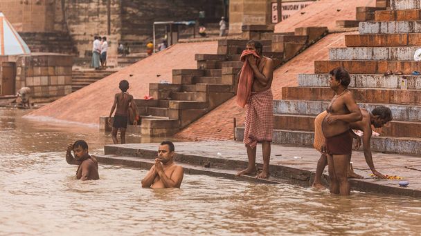 Gli indiani vivono, pregano e fanno il bagno nel fiume Gange (Ganga) al ghat con vecchi edifici sullo sfondo a Varanasi, Uttar Pradesh, India
. - Foto, immagini