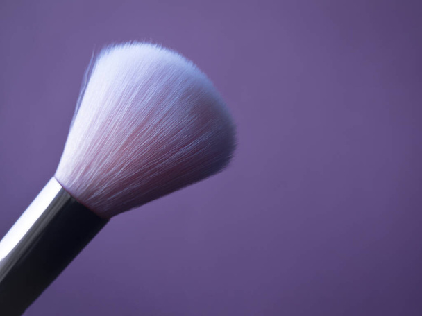 Cepillo de base de nylon rosa para maquillaje primer plano aislado sobre fondo púrpura borrosa con espacio de copia. Accesorios de maquillaje profesional
. - Foto, Imagen