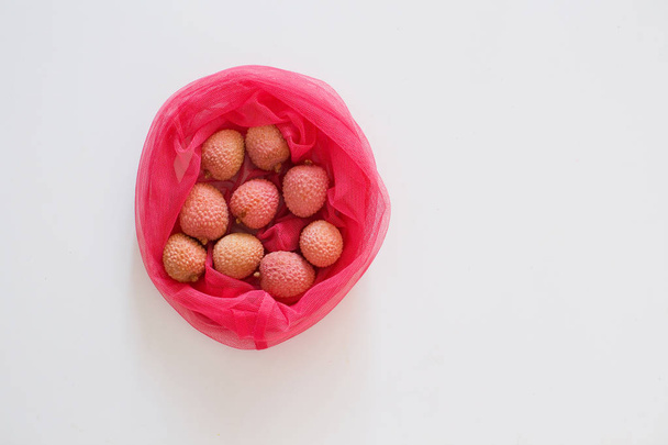 Fresh lychee in pink eco bag isolated on the white background. Tasty fruits - Fotó, kép