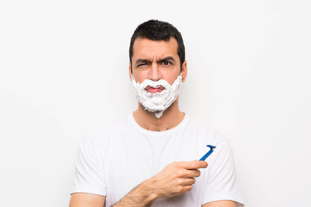 Homme rasant sa barbe sur fond blanc isolé avec une expression triste et déprimée
 - Photo, image