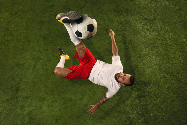 Top view of caucasian football or soccer player on green background of grass - Foto, imagen