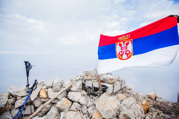 Szerbia nemzeti zászlója a hegycsúcson, a táj ködös téli napja  - Fotó, kép