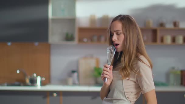 Woman singing song in whisker on kitchen. Girl having fun at home - Video, Çekim
