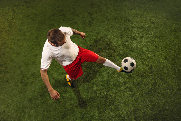 Top view of caucasian football or soccer player on green background of grass - Valokuva, kuva