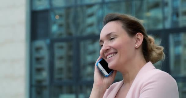 Closeup face of an adult woman talking by mobile phone.  Smiling caucasian woman calling by  cell phone, outdoors. Happy lady  with mobile phone.  Real time. 4k.  - Záběry, video