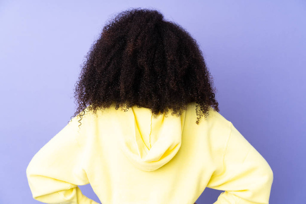 Young african american woman isolated on purple background in back position - Foto, afbeelding