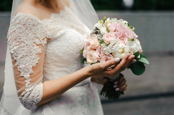 une mariée dans une robe de mariée en dentelle blanche et un voile tenant un bouquet de fleurs de mariage
 - Photo, image