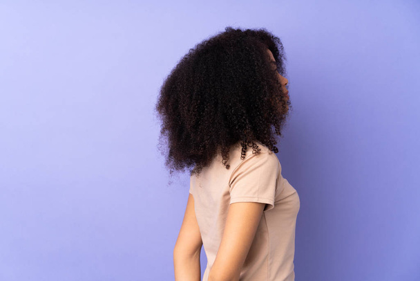 Young african american woman isolated on purple background in back position and looking back - 写真・画像
