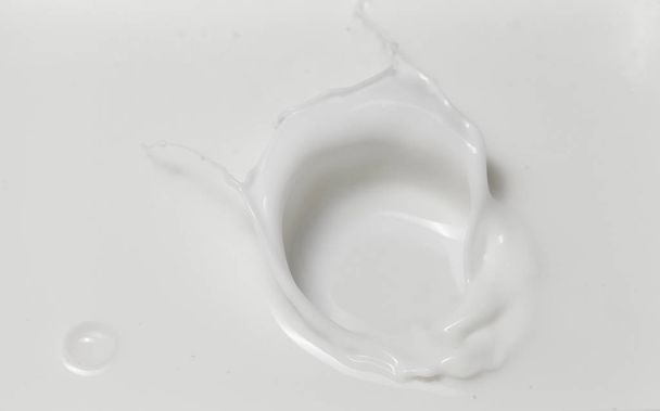 Verse melk gieten waardoor een kroon plons in een melkplas. Bovenaanzicht, geïsoleerd op grijs-witte achtergrond. - Foto, afbeelding