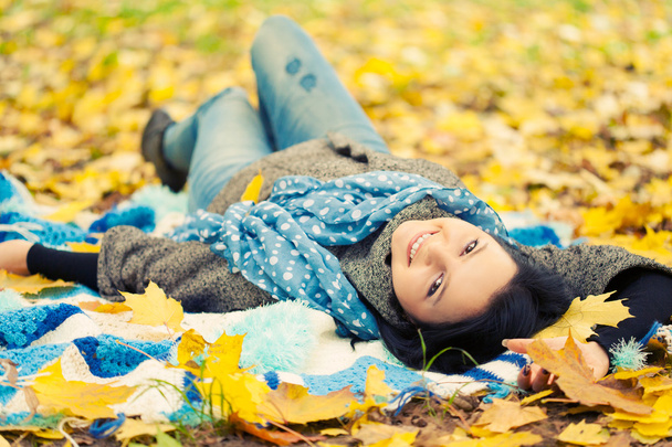 Young woman laying in autumn leaves - Foto, imagen