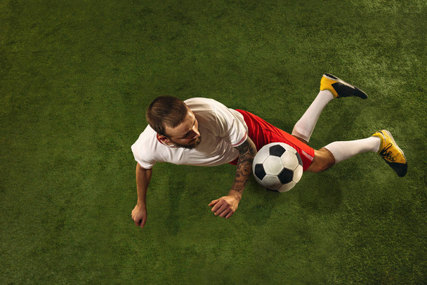 Top view of caucasian football or soccer player on green background of grass - Foto, Imagen