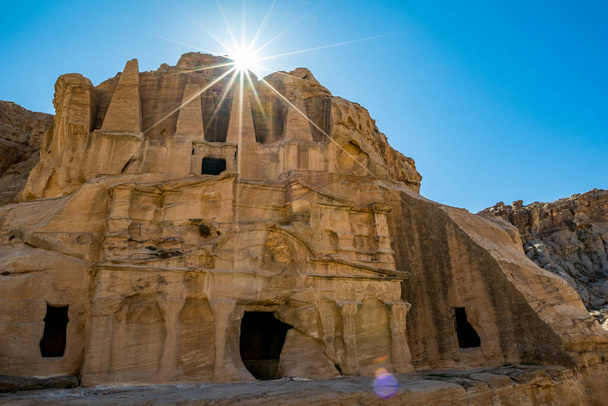 Petra, Jordania. Impresionantes rayos de luz solar, efecto de difracción de luz sobre la tumba del Obelisco o Bab As Siq Triclinium en el hermoso reino de Oriente Medio. Nublado cielo azul claro cálido día de invierno
 - Foto, Imagen