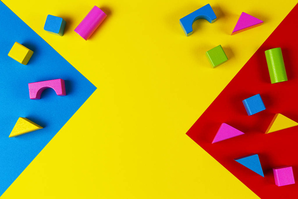 Wooden colorful blocks on geometric yellow blue red background. Top view - Photo, Image
