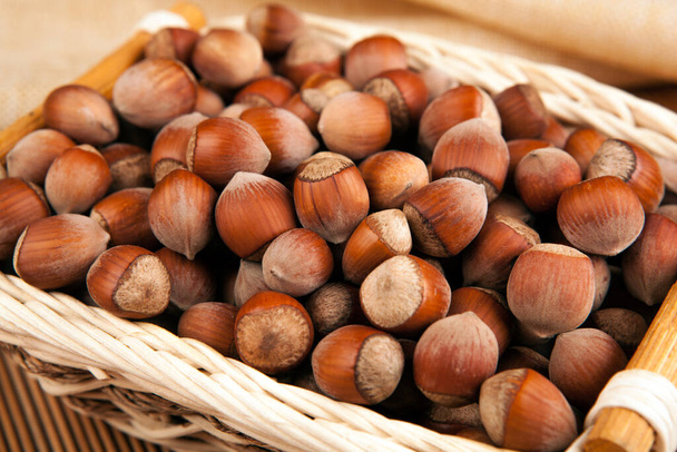 whole hazelnut kernels in a wicker basket close up - Photo, Image