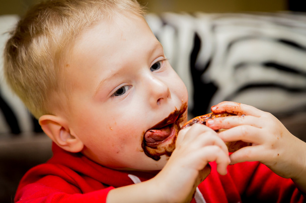 kisfiú, enni a fánk, csokoládé - Fotó, kép