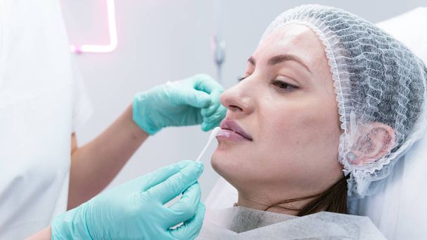 A fiatal kozmetikus orvos készül beadni az injekciót a női ajkak. Az orvos kozmetológus ajaknagyobbító eljárást végez. Fogalma szépségszalon és plasztikai sebészet klinika. - Fotó, kép