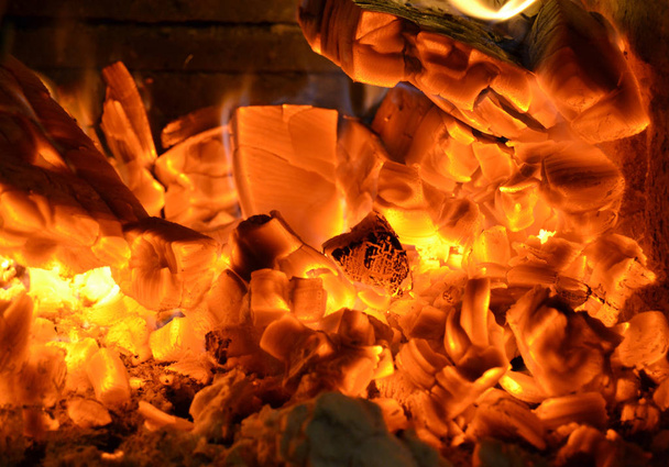炎の明るい閃光のクローズアップ。夜は熱い石炭と木を燃やす。赤い粒子の木を加熱することによって焼かれた。焚き火とキャンプのコンセプト - 写真・画像