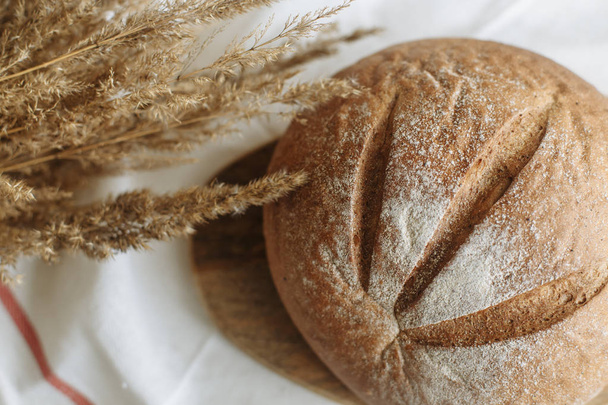 Loaf of bread on a board on a white tablecloth - Фото, зображення