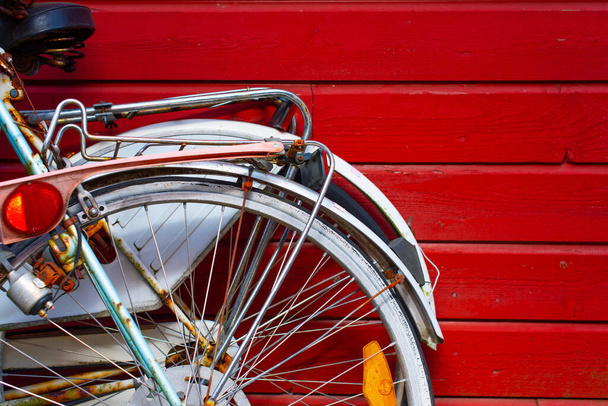 Δύο παλιά ποδήλατα ακουμπισμένα σε έναν κόκκινο, ξύλινο τοίχο. - Φωτογραφία, εικόνα