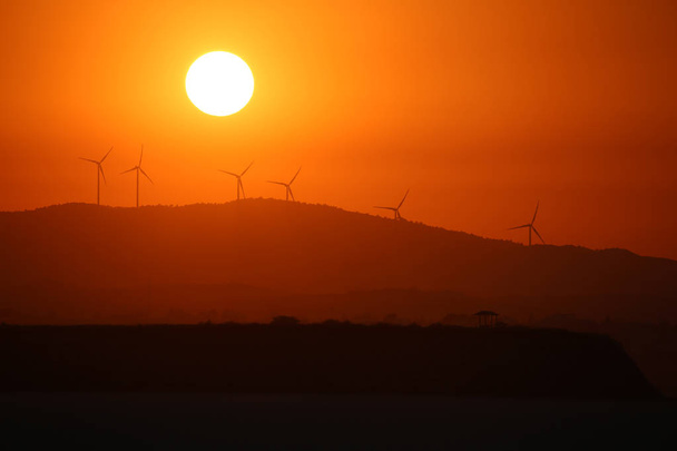 Windenergie generatoren op de achtergrond van zonsondergang boven droog zoutmeer in Cyprus Larnaca in de zomer - Foto, afbeelding