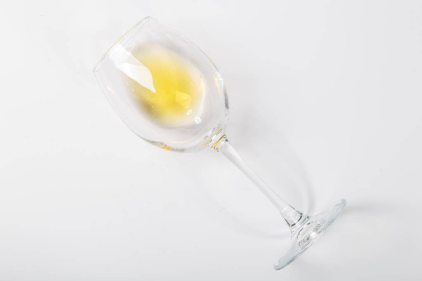 a glass of white wine lies on its side on a white background - Foto, Bild