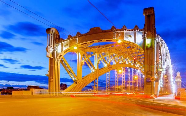Vibráló kilátás a híres város folyó acél crossover címe The Peter the Great bridge in Saint - Petersburg és fényjelzők naplementekor - Fotó, kép
