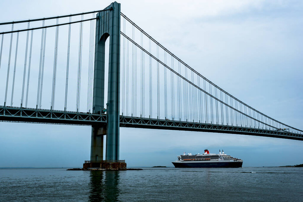June 10, 2018 - Bay Ridge, New York, USA: RMS Queen Mary 2 passing under the Verrazano-Narrows Bridge en route to Southampton, UK, on her 301st transatlantic voyage. - Photo, Image