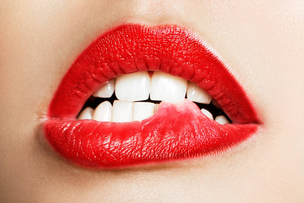 Close-up of the white teeth of a woman biting her lips - Foto, Imagen