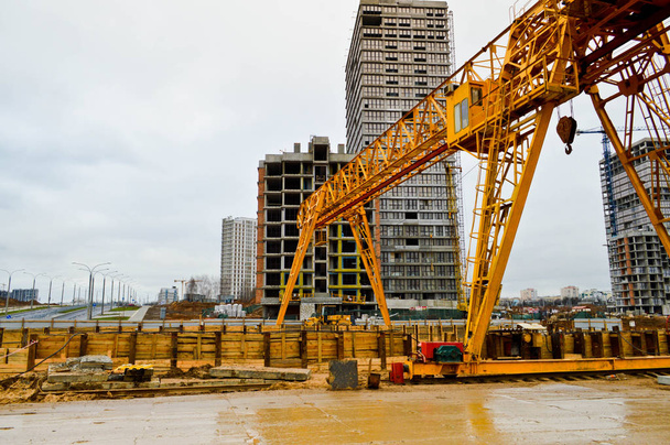 Wysoka, żółta konstrukcja nośna z metalu ciężkiego Stacjonarna, potężna suwnica bramowa typu mostowego na podporach do podnoszenia ładunków na nowoczesnym placu budowy budynków i domów - Zdjęcie, obraz