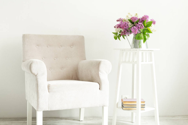 A cozy armchair and a bouquet of lilacs. A place to read or a cup of coffee. Cozy Scandinavian interior. Minimalism - Image - Photo, Image