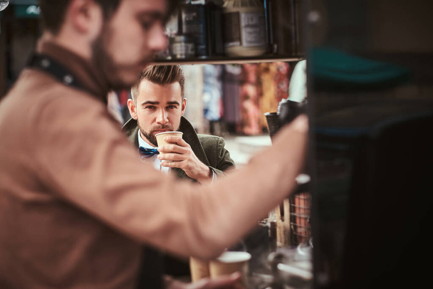Elegáns férfi ügyfél ül a szabadban, a barista mellett egy mobil kávézóban egy városi áruházban. - Fotó, kép