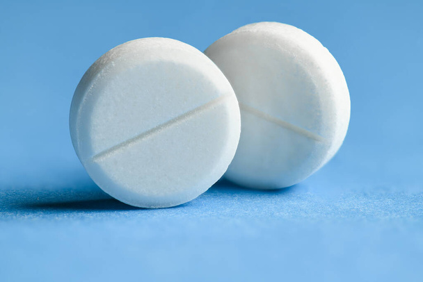 White pills on blue background macro photo - concept of medicine and medication treatment, health care - Valokuva, kuva