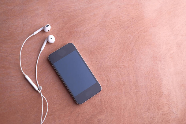 shora pohled na chytrý telefon a sluchátka na stole  - Fotografie, Obrázek
