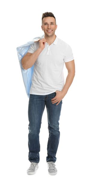 Man holding hanger with shirt in plastic bag on white background. Dry-cleaning service - Фото, изображение