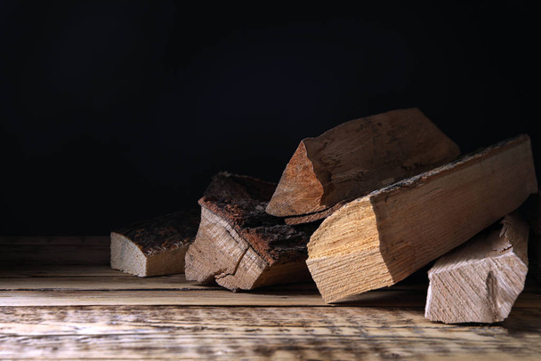 Cut firewood on table against black background - Photo, Image